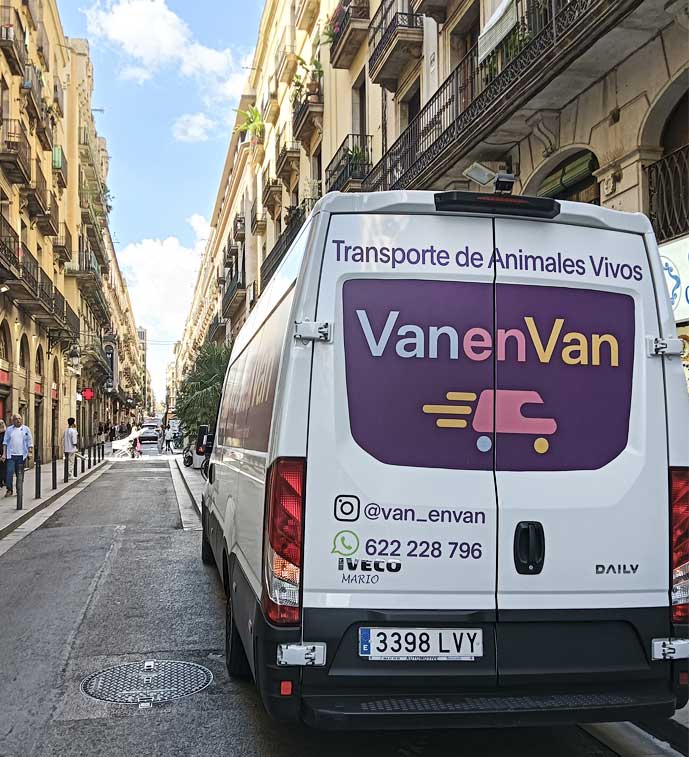 Furgoneta VanenVan Transporte de mascotas Furgoneta de transporte de animales VanenVan aparcada en una calle, rodeada de edificios.